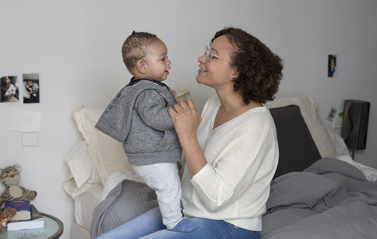 Une jeune maman joue avec son bébé debout sur ses genoux
