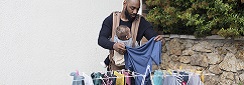 un père avec un porte-bébé étend du linge