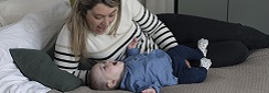 une maman et son bébé interagissent par la voix sur le lit
