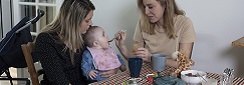 deux femmes dont une donne à manger à un bébé
