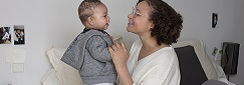 une maman aide son bebe à se tenir debout