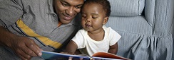 Un papa en train de lire une histoire à un tout petit.
