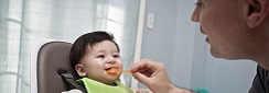 Bébé nourri par un parent (purée de légume ou fruit).