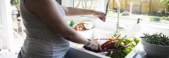 une femme enceinte passe sous l'eau du robinet des fruits et légumes