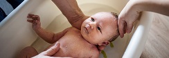 un adulte fait prendre un bain à un nouveau-né