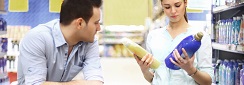 un couple au supermarché, la femme compare des étiquettes de lessives