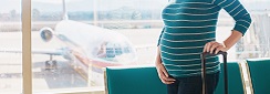une femme enceinte à l'aéroport avec une valise