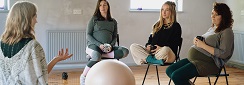trois femmes enceintes discutent avec une professionnelle autour d'un gros ballon