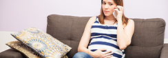 Une femme enceinte est au téléphone, assise sur son canapé