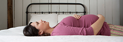Une femme enceinte est allongée sur le dos sur son lit