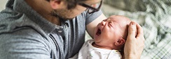un nourrisson qui pleure dans les bras d'un homme