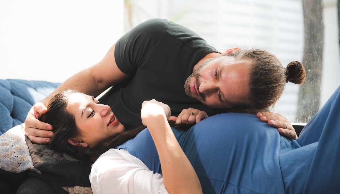 un homme écoute le ventre de sa compagne enceinte