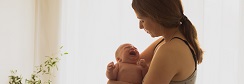 une femme regarde son nourrisson qui pleure dans ses bras