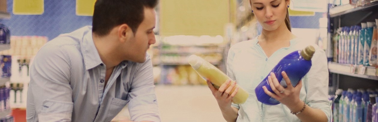 couple au supermarché qui compare deux bidons de lessive