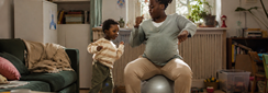un jeune enfant danse à côté de sa maman dans son salon