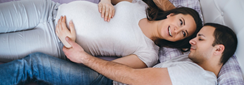 un moment de tendresse entre une femme enceinte et son compagnon, allongés