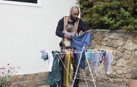 un père avec un porte-bébé étend du linge