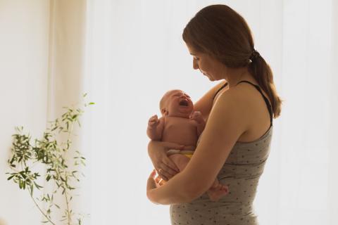 une femme regarde son nourrisson qui pleure dans ses bras