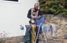 un père avec un porte-bébé étend du linge