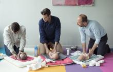 trois hommes dans un atelier de futurs papas apprennent à changer une couche sur des baigneurs