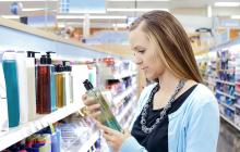 femme au rayon hygiène d'un supermarché inspecte l'étiquette d'un shampooing
