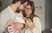 de jeunes parents regardent leur nourrisson tenu dans les bras du père
