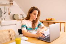 une femme chez elle devant des papiers et un ordinateur