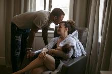 un homme embrasse le front d'une femme en train d'allaiter son nourrisson