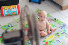 un bébé en couche devant un ventilateur dans le salon